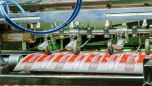 Machine industrielle imprimant des rouleaux de papier rouge et blanc en mouvement rapide